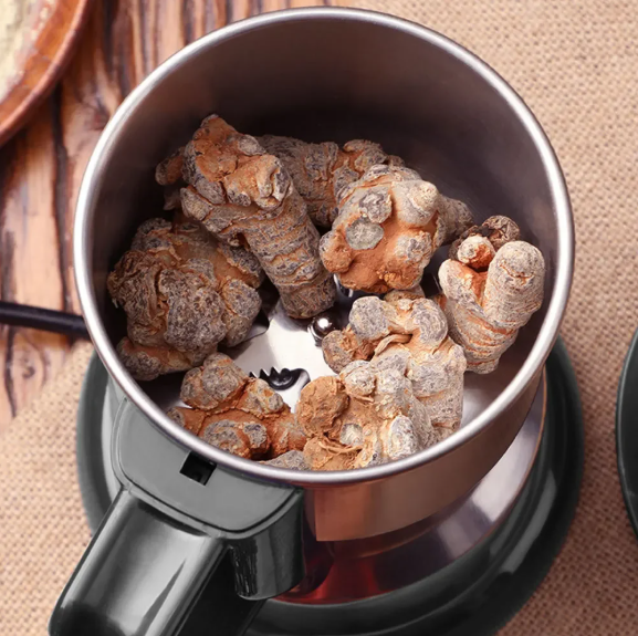 Metallic Multifunctional Mini Grinder filled with dried roots on a wooden surface