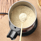 Spoonful of powder over a Multifunctional Mini Grinder on a wooden surface