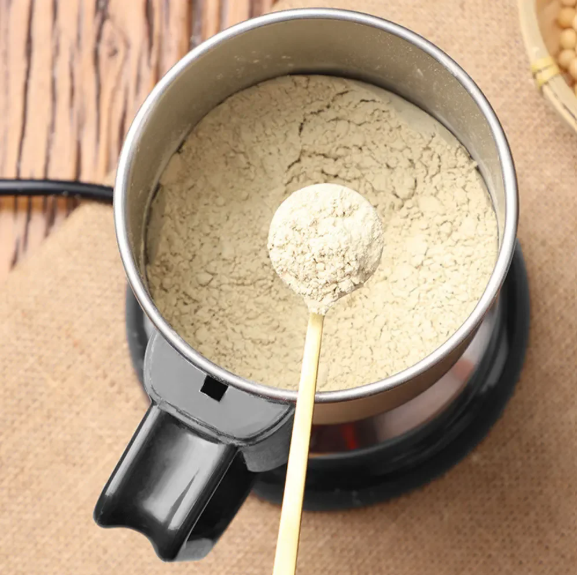Spoonful of powder over a Multifunctional Mini Grinder on a wooden surface