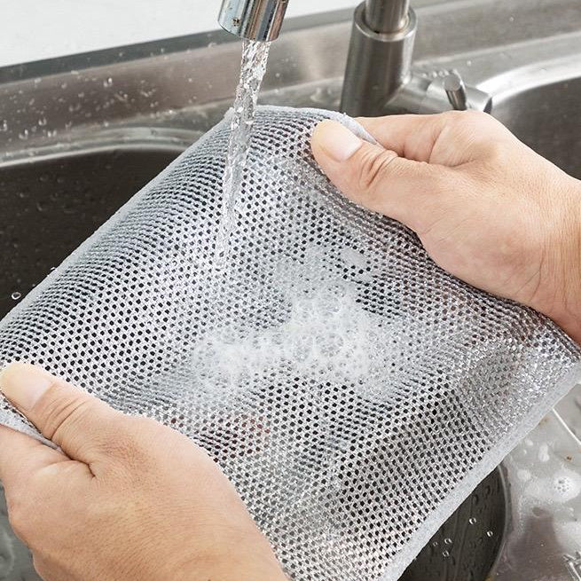Person washing a mesh bag under running water in a sink with text on the screen.